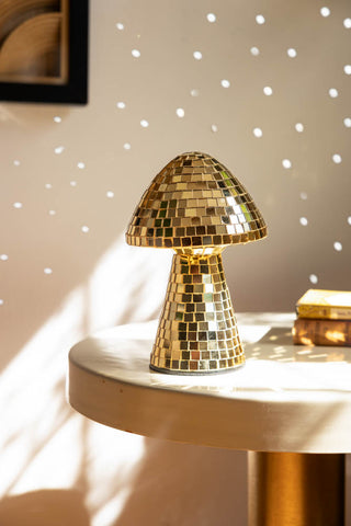The Small Disco Mushroom Ornament displayed on a table in the sunshine, reflecting light onto the wall in the background.