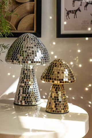 The Small and Large Disco Mushroom Ornaments displayed on a table in the sunshine, reflecting light on the surroundings.