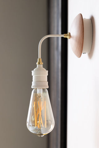 Lifestyle image of the Squirrel Cage E27 6W Clear LED Light Bulb on a wall lamp.