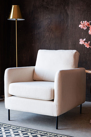 The Edie Natural Armchair styled with a lamp and flowers.