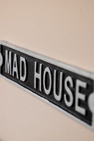 Close-up of The Madhouse Sign displayed on a neutral wall.