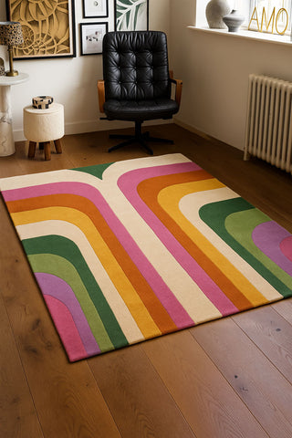 A styled image of the The Romy Retro Rug in Pink on a wooden floor.