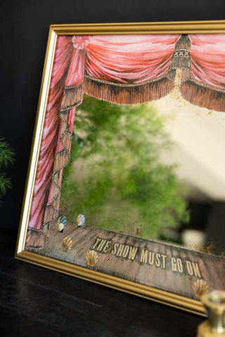 Decorative mirror with theater stage design and 'The Show Must Go On' text.
