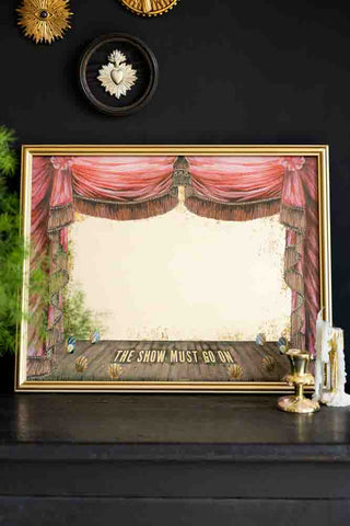 Framed theater curtain print with 'The Show Must Go On' text on a black background