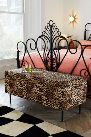 The Velvet Leopard Print Ottoman Storage Bench styled at the end of a bed.
