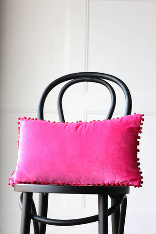 Lifestyle image of the Hot Pink Pom Pom Velvet Cushion