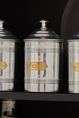 Image of the Vintage-Style Cafe’ Coffee Tin on a black shelf paired with the Vintage Sugar and Tea Tins.