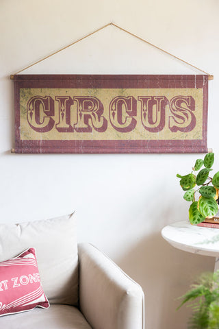 The Vintage-Style Circus Wall Art styled on a off white wall with a velvet chair underneath with a red cushion on it