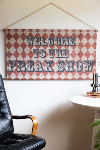 The Vintage-Style Freak Show Wall Art displayed on a light wall above a leather and a white side table with a black and white ornament