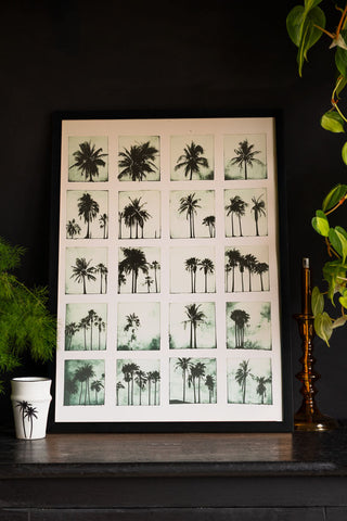 Lifestyle image of the Vintage-Style Polaroid Palms A2 Art Print in a black frame on a dark background.