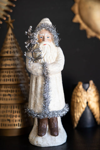 Decorative figure of a bearded man in a long coat with a tree, against a dark background.