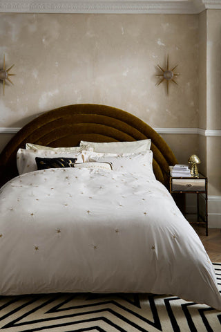 Lifestyle image of the White Falling Star Duvet Cover and Pillow Case Set styled on a bed in a bedroom with various home accessories.