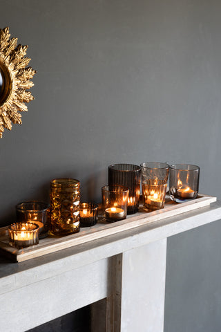 Image of the votives in amber styled with lit tealights on a fireplace.