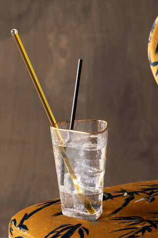The Yellow Glass Cocktail Stirrer styled in a glass of gin with a straw and displayed on a bar stool.