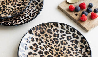 The Set of 4 Natural Leopard Love Plates displayed on a white table, with a wooden chopping board, berries and cutlery.