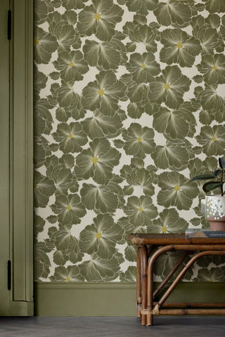 Rockett St George bohemian bloom wallpaper features large pretty flowers with orange centres. The flowers are in moss green, The image shows a room with matching woodwork. 