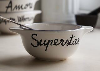 Lifestyle image of the Super Star Bowl displayed on a kitchen worktop with a spoon inside, with other bowls and kitchen accessories in the background.