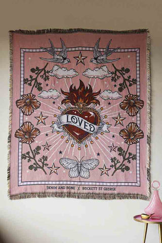 A pretty pink throw that's been put on the wall. The throw features a a large heart, flowers, butterflies and stars.