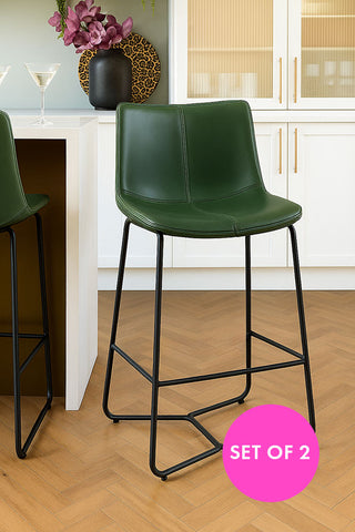 Set of two green bar stools with black legs in a kitchen setting.