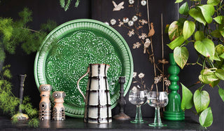 Lifestyle image of new Rockett St George kitchenware arranged on a black sideboard with candlesticks and plants.