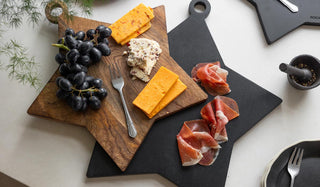 Lifestyle image of the new Rockett St George star serving boards displayed with fruit, cheeses and meat and various other kitchen accessories on a white table.