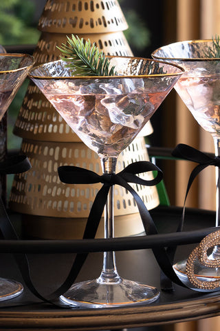 Two martini glasses with decorative ribbons and a blurred background