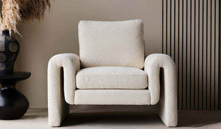 A stunning boucle armchair with unusual curved arms and a large back pillow. 
