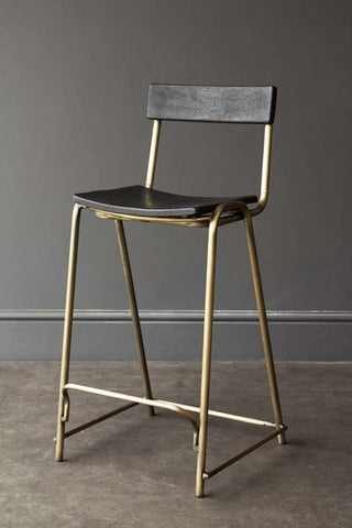 Black and gold profile picture of a bar stool with gold legs and a black base back plate. 