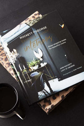 lifestyle image of Extraordinary Interiors by Jane Rockett & Lucy St George with leopard print book and black mug on black table