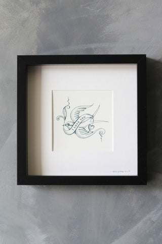 lifestyle image of i love you bird tattoo art work by brigitte herrod in black square frame on distressed grey wall