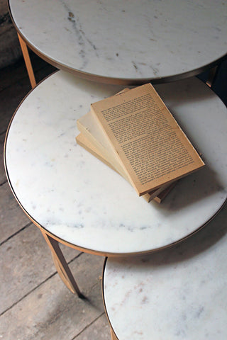 round nest of 3 marble side tables on pale wooden flooring and vintage book detail image