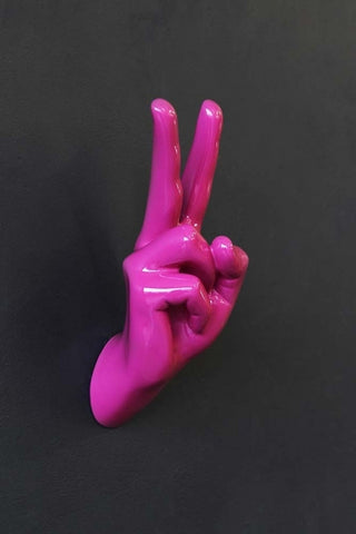 lifestyle image of peace hand wall art & coat hook hot pink on black wall background