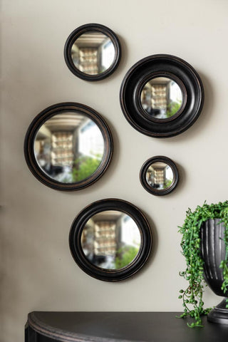 A collection of small round wall mirrors styled on a white wall