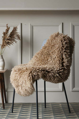 Lifestyle image of the Curly Sheepskin Rug In Butterscotch on a chair