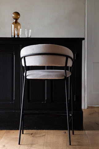 Lifestyle image of the Mink Curved bar stool facing a bar