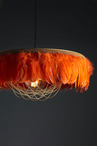 Close-up image of the Juliette Fabulous Feather Chandelier Featuring Chains in Burnt Orange on a dark background