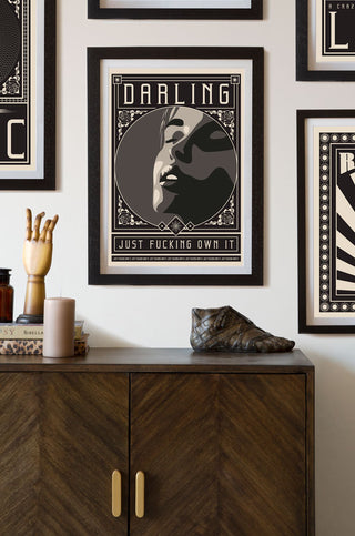 Lifestyle image of the Framed Darling Just Fucking Own It Art Print hanging on a wall