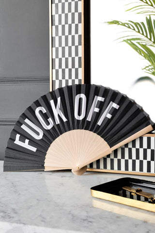 Lifestyle image of the Fuck Off Wooden Fan propped up against a wall. 