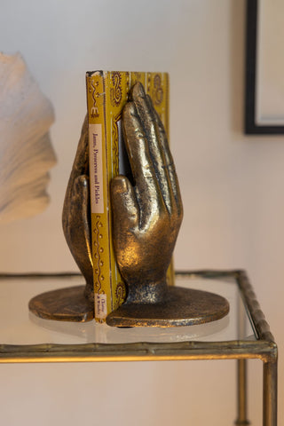 Lifestyle image of the Gold Holding Hands Bookends on a glass shelf