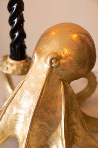 Detail image of gold octopus candlestick holder's face with black candles