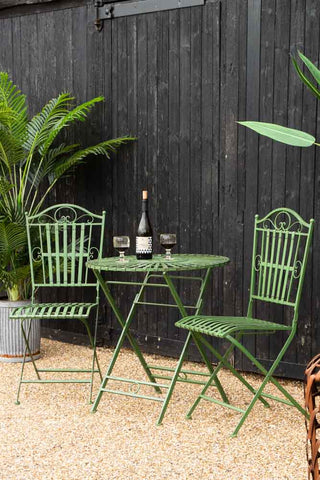 Lifestyle image of the Green Metal Garden Table & Chair Set in a garden