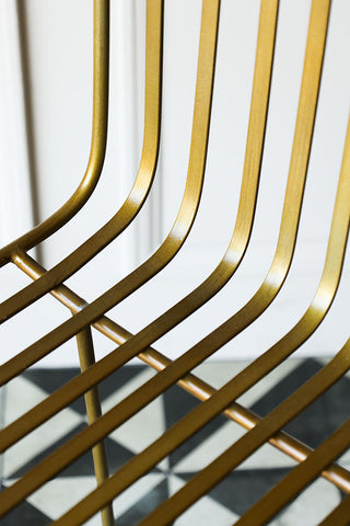 A detailed view of the gold curved bar stool.