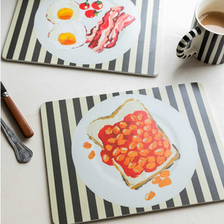 A picture  of two placemats, one of which features bacon and eggs and the other beans on toast