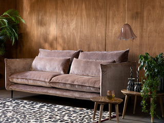A large smoky grey sofa styled with a rug and a nest of tables