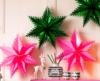 An image of green and pink metallic stars hanging over a mantel 