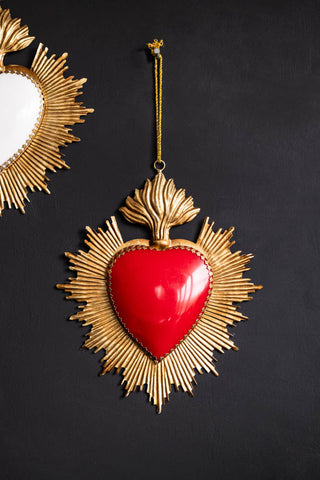A beautiful red Milagro heart styled as wall decor against a soft black wall