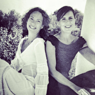 Lucy St George and Jane Rockett in summer dresses, sitting side by side and smiling at the camera