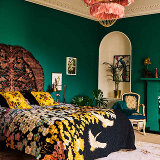 Image of a green bedroom with a wendy morrison throw on the bed and a pink feather chandelier light.