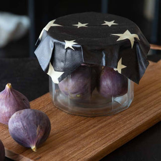 image of black beeswax food wrap with white stars covering a glass jar filled with figs