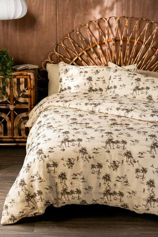 A beautiful bed with a wicker headboard and pretty floral bedding, styled next to a wooden bedside table and wall light